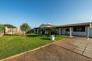 A residential property with a well-maintained lawn, a patio area, and a fenced garden.