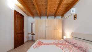A bedroom with a bed, wooden wardrobe, and an air conditioning unit. - Vacation Home "Casa Silvia" with Private Terrace & Wi-Fi (Calasetta)