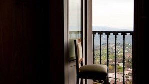 Ein Zimmer mit Blick durch eine Balkontür, ein Sessel und ein Gemälde an der Wand.