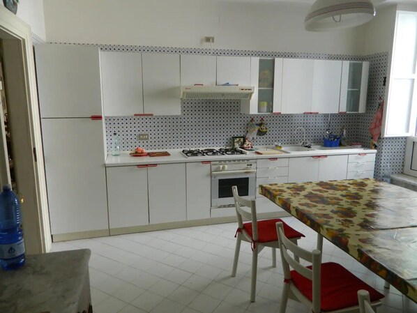 A kitchen with white cabinets, a gas stove, a sink, and a dining table with chairs.
