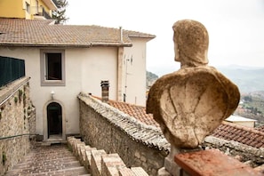Una estatua de piedra domina una escalera que conduce a un edificio con tejado de tejas.