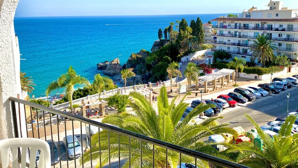 A coastal hotel with balconies overlooking the sea, a parking area, and a building with multiple floors. - 'Sea Views Nice Sunset Sun' Apartment with Sea View, Shared Pool, and Wi-Fi (Nerja)