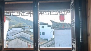 A traditional window with a view of a townscape, including buildings and a mountain.
