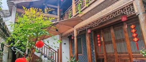 A traditional courtyard with a wooden staircase, potted plants, and a dining table.