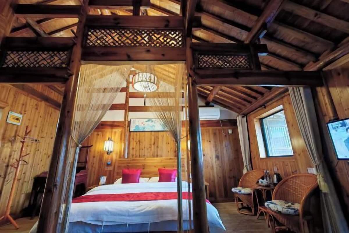 Ein Zimmer mit Holzboden, einem Bett, einem Stuhl und einem Tisch.