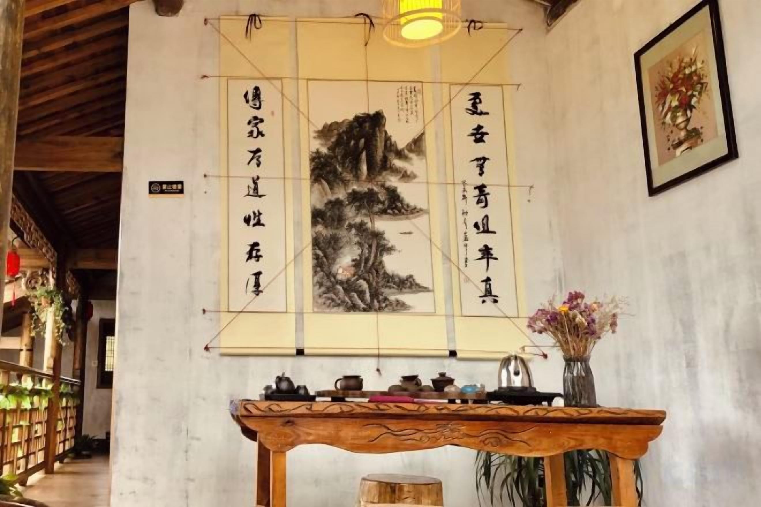 A traditional room with a wooden table, calligraphy artwork, and a framed picture on the wall.