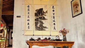 Une pièce à l’ambiance traditionnelle, avec une table en bois, des œuvres d’art calligraphiques et un tableau encadré accroché au mur.