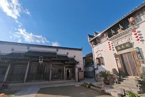 Ein traditioneller Innenhof mit einem Gebäude, das ein Ziegeldach und Holztüren hat.