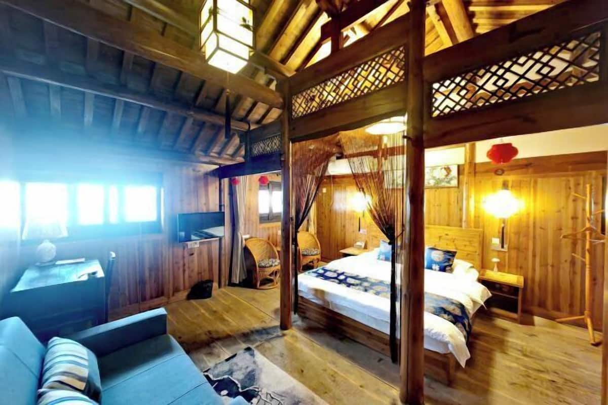 Ein Zimmer mit Holzboden, einem Bett, einer Schlafcouch, einem Schreibtisch und einem Fernseher.