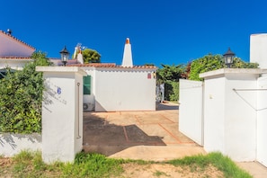Un patio con un edificio blanco, una puerta y un cielo azul despejado.