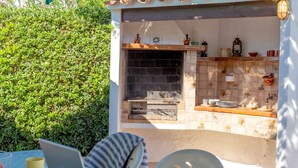 Ein Außenbereich mit Küche, einem Kamin aus Ziegelsteinen, einer gefliesten Rückwand und diversen Küchengeräten.