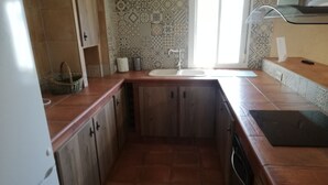 Una cocina con un lavamanos, armarios y una ventana.