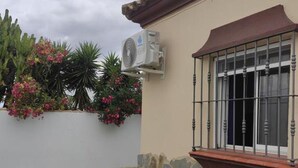 Una casa con un muro de piedra, una ventana con barrotes metálicos y un equipo de aire acondicionado instalado en la pared.