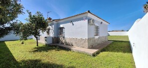 Un petit bâtiment blanc, avec un socle en pierre, un toit en tuiles et un petit porche.