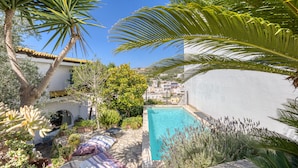 A pool surrounded by lush greenery and a white building with a tiled roof. - Villa 'Blu La Cambusa' with Shared Pool, Wi-Fi and Air Conditioning (Castro)