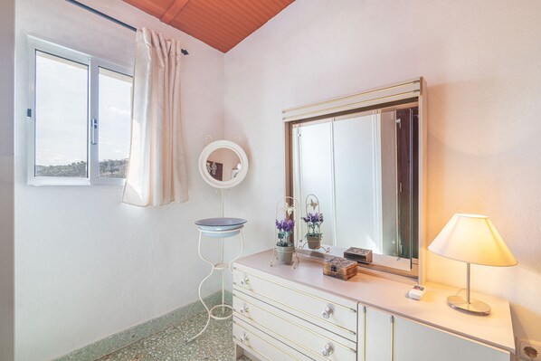 Une salle de bain avec un meuble-lavabo, un miroir, une lampe et une fenêtre donnant sur un beau paysage.