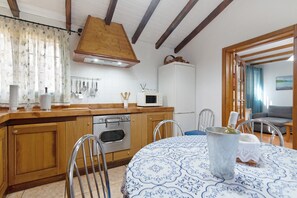 Una cucina con mobili in legno, un forno a microonde e un tavolo da pranzo con sedie.