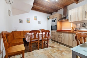 A kitchen with wooden cabinets, a dining table with chairs, and a tiled floor. - 'El Pajar' with Sea Views, Wi-Fi, and Air Conditioning (Vega de San Mateo)