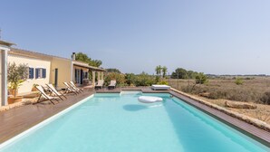 A swimming pool with lounge chairs, a floating ring, and a view of the countryside. - Holiday Home 'Can Juan Pedro' with Sea View, Wi-Fi and Air Conditioning (Formentera)