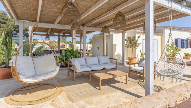 An outdoor patio with a wooden table, two sofas, and a hanging chair. - Holiday Home 'Can Juan Pedro' with Sea View, Wi-Fi and Air Conditioning (Formentera)
