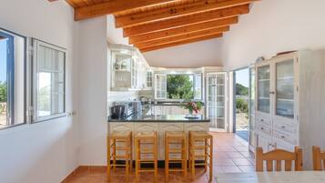 A kitchen with a central island, wooden stools, and a view to the outside.