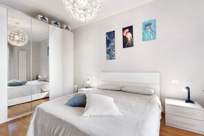 A modern bedroom with a large bed, bedside tables, a wardrobe, and artwork on the walls. - Holiday Apartment "La Casetta Di Ale" with 2 Balconies & Wi-Fi (La Spezia)