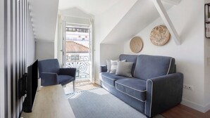 A modern living room with a sofa, armchairs, and a TV. - Apartment "Casa Ribeiro - Praia Chic" with Balcony & Wi-Fi (Nazaré)