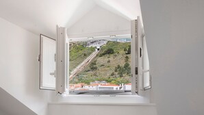 A room with a window overlooking a hillside and a bridge. - Apartment "Casa Ribeiro - Praia Chic" with Balcony & Wi-Fi (Nazaré)