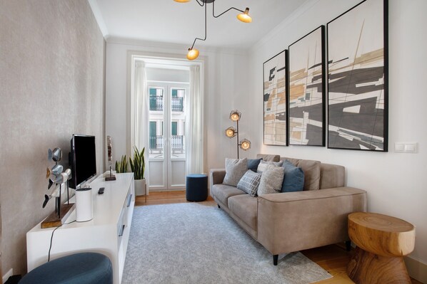 A modern living room with a sofa, a coffee table, a TV, and artwork on the wall.
