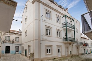 A multi-story building with a balcony, a door, and a window.