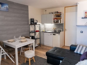 Ett kompakt bostadsutrymme med en matplats, ett litet kök och en sittgrupp.