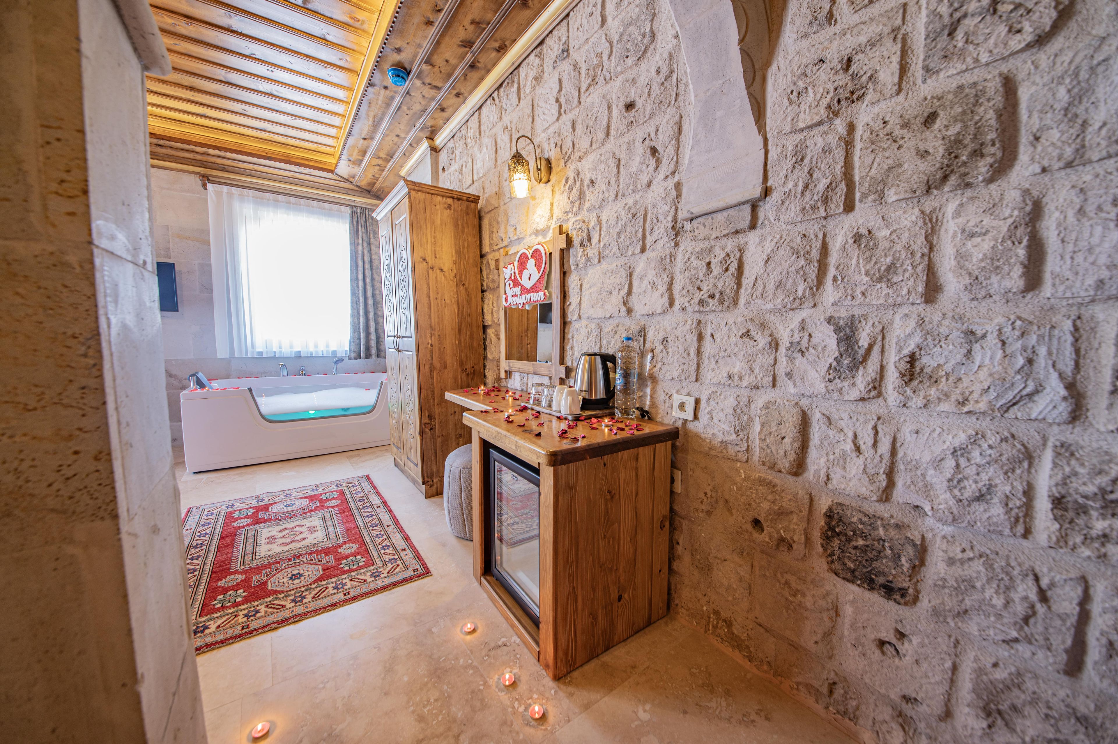 Un baño con pared de piedra, tocador de madera, espejo y bañera.