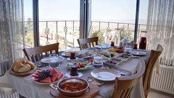 Taula preparada per a dinar amb diversos plats i begudes, amb vista a un paisatge urbà.