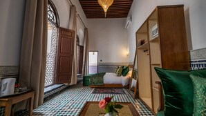 A room with a bed, a sofa, a coffee table with a vase, and a decorative ceiling light. - Riad Fes Ziyat & Spa (Fes)