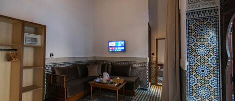 A living room with a sofa, coffee table, and a TV mounted on the wall.
