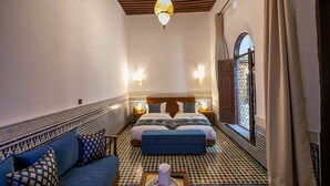 A room with a bed, a sofa, patterned walls, and a hanging light fixture. - Riad Fes Ziyat & Spa (Fes)