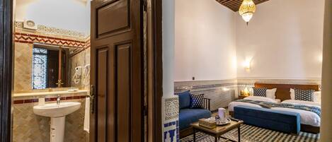 Habitación de hotel con baño, cama, sofá y una pequeña mesa.