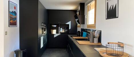 Una cocina moderna con armarios oscuros, una isla central y vista al área de comedor.