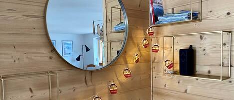 Un interior de madera con un espejo redondo, estanterías y luces de cadena.