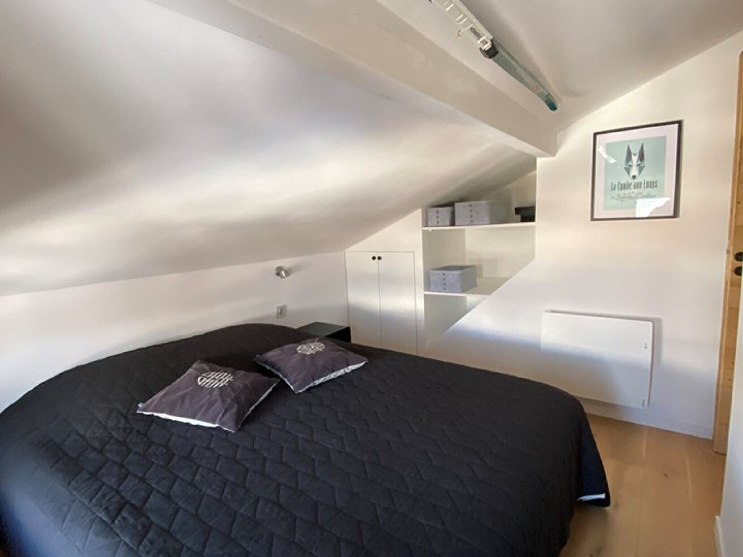 A bedroom with a large bed, a ceiling fan, and built-in storage cabinets.