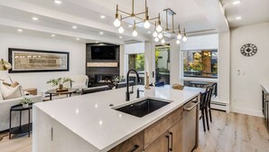 Een moderne keuken met een groot kookeiland, inbouwapparatuur en een eethoek met uitzicht.