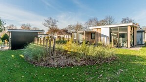 A modern house with a well-maintained lawn, a small shed, and a glass-enclosed room.