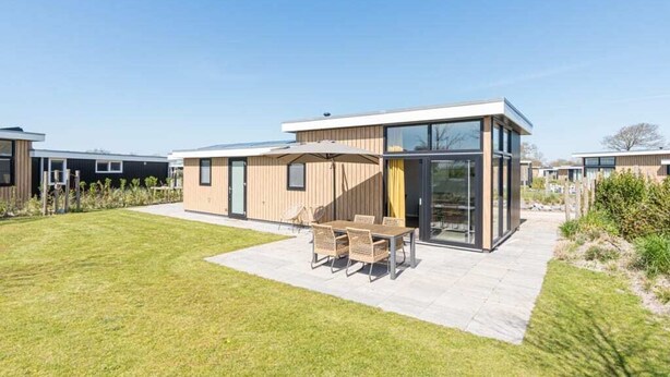 Ein modernes Haus mit Terrasse, Essbereich und einem großen Glasfenster.