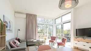 A modern living room with a sofa, chairs, a coffee table, and a TV. - This attractive chalet is located on a spacious plot and is suitable for 4 people. The garden, laid (Burgh-Haamstede)