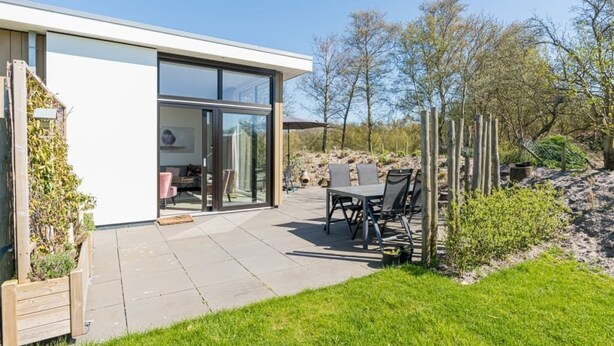 A modern house with a patio, outdoor seating, and a garden. - This attractive chalet is located on a spacious plot and is suitable for 4 people. The garden, laid (Burgh-Haamstede)