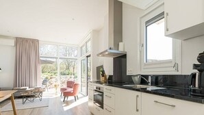 A modern kitchen with white cabinets, a black countertop, and a window above the sink. - This attractive chalet is located on a spacious plot and is suitable for 4 people. The garden, laid (Burgh-Haamstede)