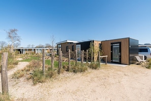 Een moderne camping met meerdere caravans, elk met een eigen toegang en een klein zitgedeelte buiten.