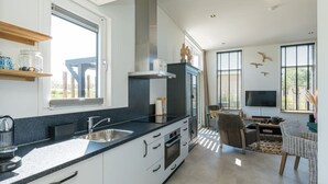 Una cocina moderna con una isla grande, horno empotrado y comedor con televisión y asientos.