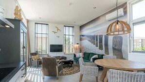 Una sala moderna con televisor, sofá, mesa de comedor y sillas.
