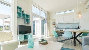 A modern kitchen with white cabinets, a dining area with a white table and chairs, and a large window providing natural light. - Fan of Ibiza "style"? Then we can assure you that you will feel at home here! Via the shell path and (Burgh-Haamstede)